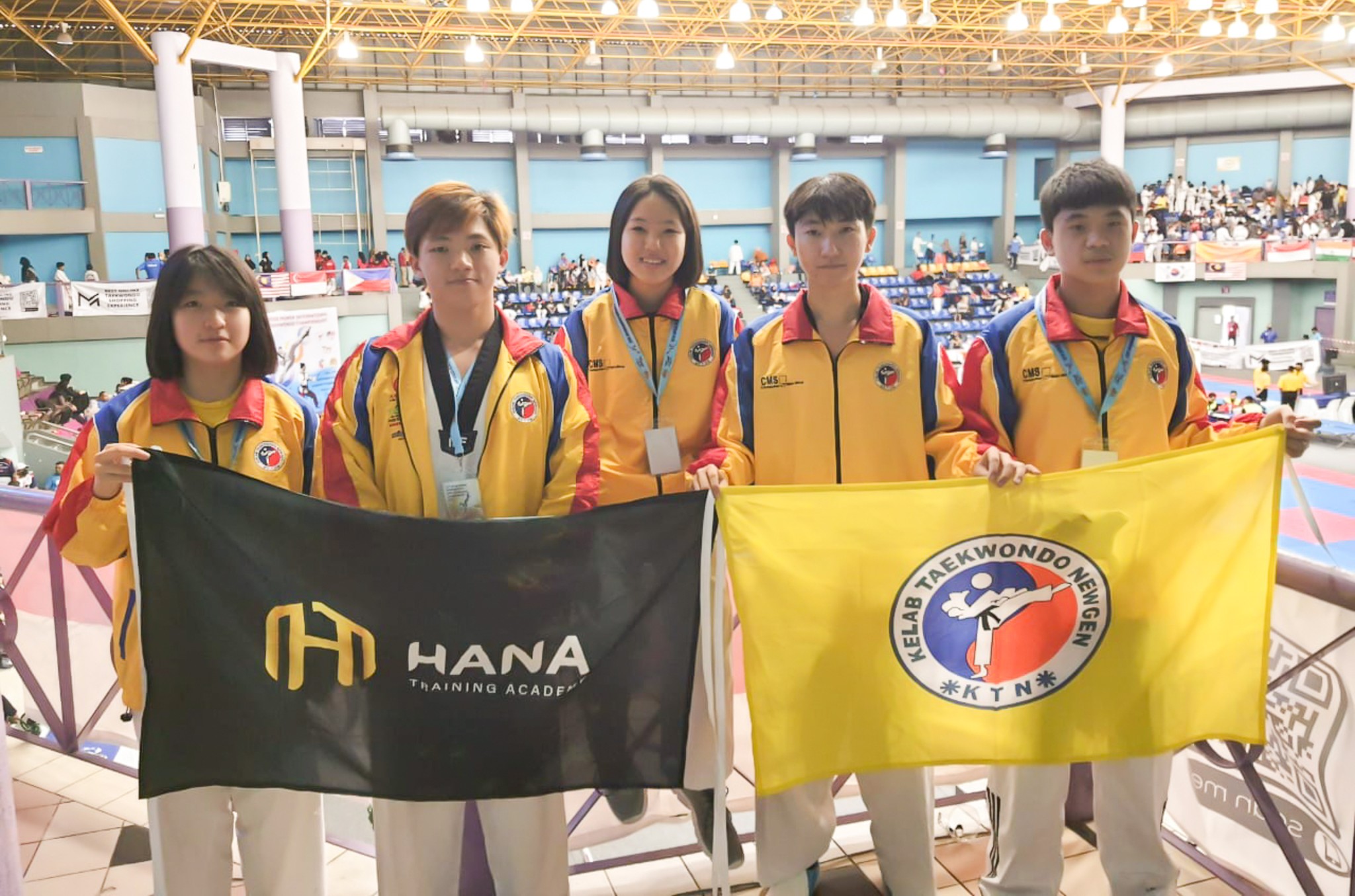 Athletes holding the Hana Training Academy and Kelab Taekwondo Newgen flags